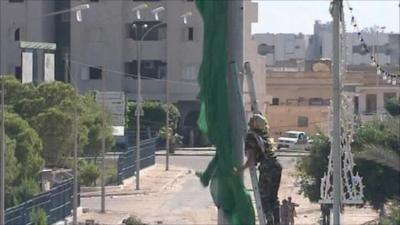 Fighter taking down flag on outskirts of Sirte