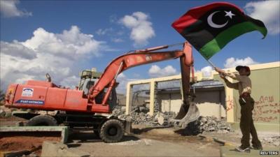 Boy waving a flag as a mechanical digger gets to work