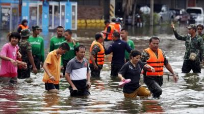 Soldiers help workers and civilians evacuate a flooded area in Thailand