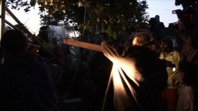 Man holds up plank of wood to police