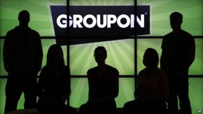 Groupon employees in front of Groupon Logo
