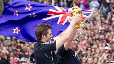 New Zealand All Blacks captain Richie McCaw (L) and coach Graham Henry (R) hold up the Web Ellis Cup during victory parade