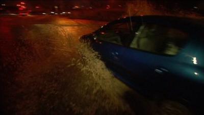 Car attempts to move along flooded road