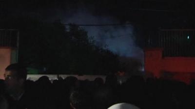 People gathered outside the prison in Van as smoke is seen rising inside the compound