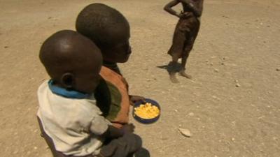 Children carrying food aid in Kenyan drought relief camp