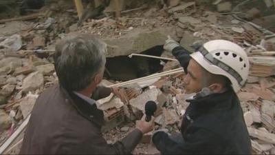 Tim Willcox and rescue worker look at collapsed building