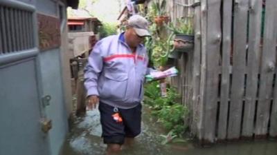 Postman Somyod Somsamai in flooded area of Bangkok