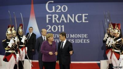 French President Nicolas Sarkozy (R) welcomes German Chancellor Angela Merkel