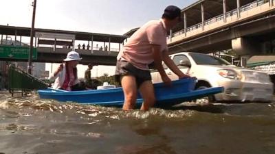 People wading through floods in Thailand