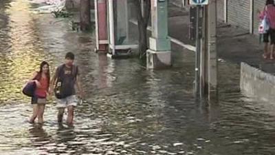 Couple walking through knee-deep waster in Bangkok street