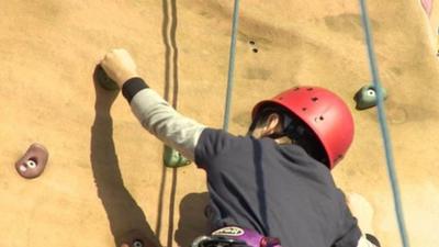 Boy climbing up a climbing wall