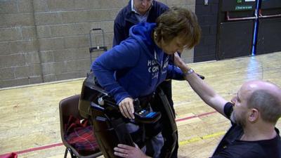 Elena Bertoldo is helped into the bionic legs by Richard Little