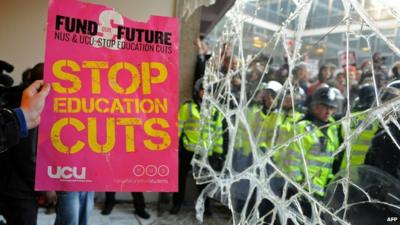 Demonstrator holds a placard next to a broken window in 2010