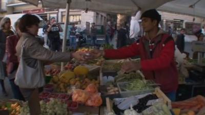 A woman buying vegetables at a market in Rome