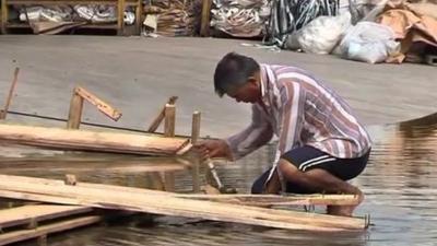 A man breaks up debris caused by flooding in Bangkok