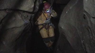 Caver hanging between rocks