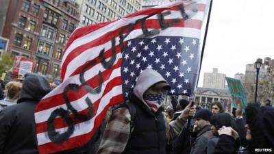 Occupy Wall Street protester carrying upside down US flag with "occupied" written on it