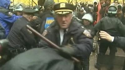 New York police officer, carrying baton, struggles with protester