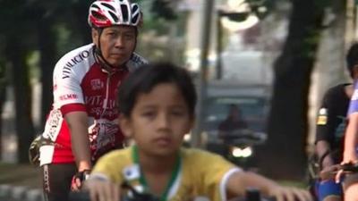 A young boy in front of a man cycling in Jakarta