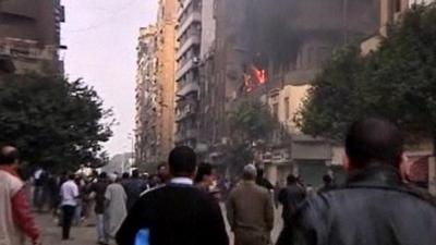 Protesters watch as flames come out of apartment window