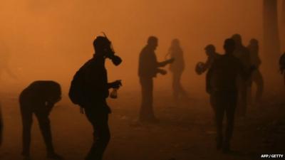 Protester wearing gas mask amidst tear gas fired by police