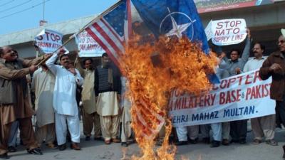 Pakistani protesters burn a US and Nato flag during a protest in Multan