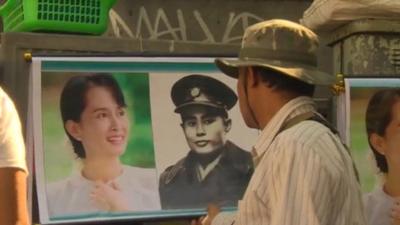 Man looks at photo of Aung San Suu Kyi