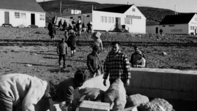 People carrying delivery supplies to houses in the Canadian Arctic