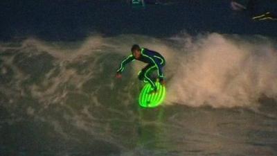 A surfer wearing a wetsuit that glows in the dark - on Bondi Beach in Australia