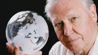 Sir David Attenborough holds a globe