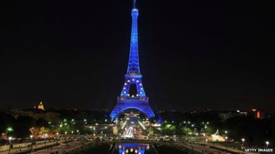 The Eiffel Tower illuminated in blue with gold stars, representing the EU flag