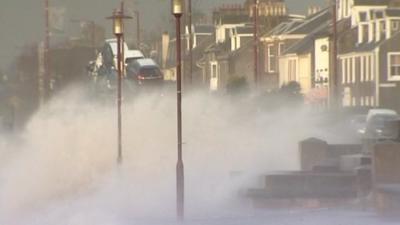 Waves crash up along a seafront promenade in Helensburgh, Scotland.