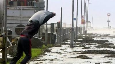 A man struggles to walk in the wind