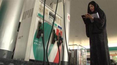 An Emirati woman standing next to a petrol pump