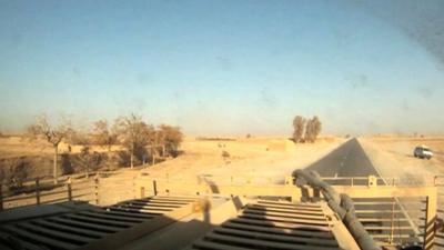 Bus is seen in distance (far right) before being hit by a roadside bomb