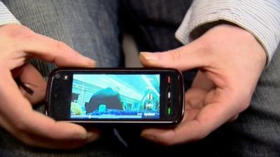 Man holding a mobile showing video footage