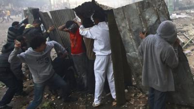 Protesters take cover near Tahrir Square in Cairo on 16 December