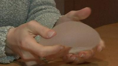 Woman holds silicone breast implant