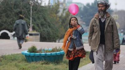 An Afghan man walks with his daughter at a park in Mazar-e-Sharif