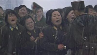 Women in military dress crying at the funeral