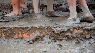 Children queue in the mud