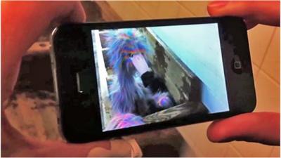 A mobile phone looking at an augmented image of a puppet in a New York subway station