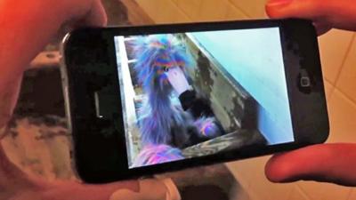 A mobile phone looking at an augmented image of a puppet in a New York subway station