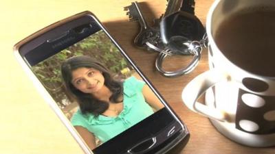 The BBC's Rajini Vaidyanathan's image on a smartphone next to some keys and a cup of tea