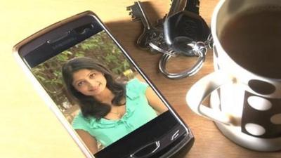 The BBC's Rajini Vaidyanathan's image on a smartphone next to some keys and a cup of tea