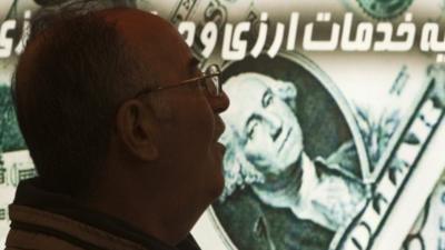 An Iranian man walks past a currency exchange shop in northern Tehran