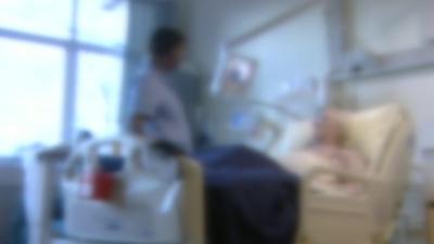 Patient in hospital bed attended by nurse