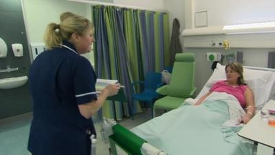 Nurse checking on patient in hospital ward