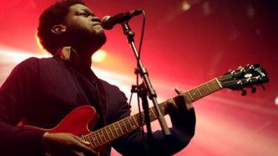 Michael Kiwanuka playing guitar and singing
