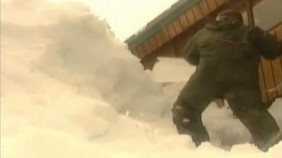 Man shovels huge pile of snow in Alaskan coastal town of Cordova.